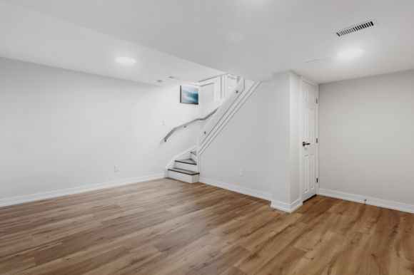 Basement Room - an empty room with a staircase and hard wood floors
